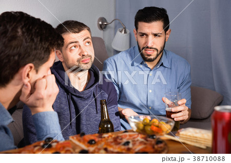 Troubled male friends talking, drinking beer with pizza at home Troubled male friends talking, drinking beer with pizza at home 38710088