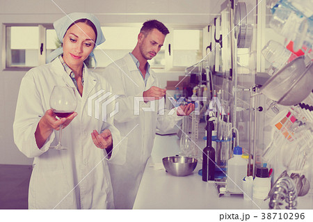 Two researchers in white coat checking wine acidity in laborator Two researchers in white coat checking wine acidity in laborator 38710296