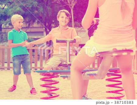 children are teetering on the swing in the playground. children are teetering on the swing in the playground. 38710383