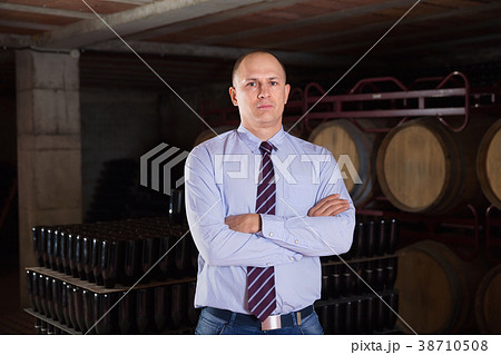 Confident succesful man winemaker posing in own winery vault Confident succesful man winemaker posing in own winery vault 38710508