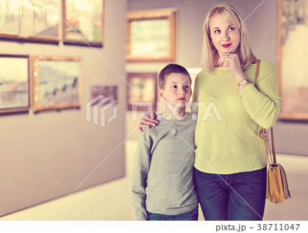 Mother and son regarding paintings in halls of museum 38711047