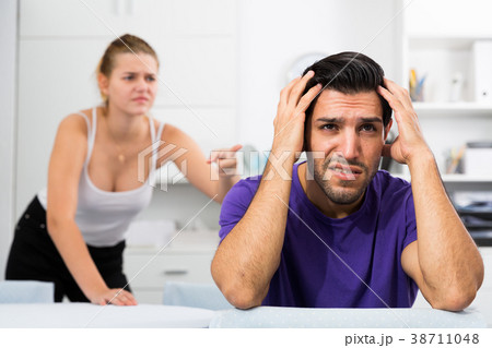 Stressed man at table with screaming wife behind 38711048