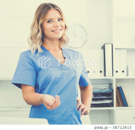 Friendly girl in doctor's uniform smiling at office 38712613