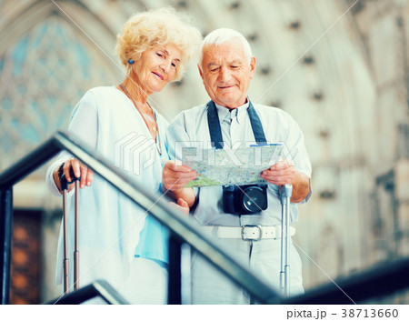 Senior couple of tourists with map and city guide walking 38713660