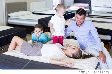 Happy woman with her family lying on back on mattress in store Happy woman with her family lying on back on mattress in store 38714779