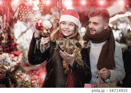 Joyful couple in Christmas hat with Christmas toys at fair 38714935