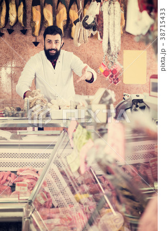 Male shop assistant demonstrating meat Male shop assistant demonstrating meat 38715433