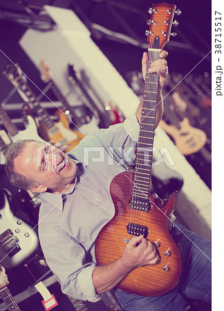 Adult man is playing on new electric guitar in studio Adult man is playing on new electric guitar in studio 38715517