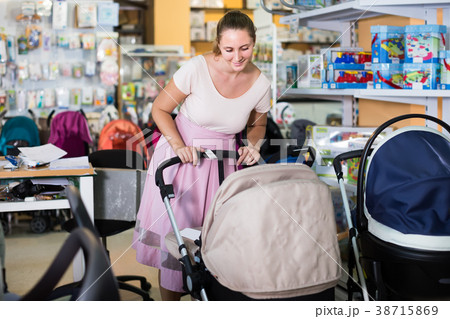 satisfied pregnant woman looking for baby carriage at kids shop satisfied pregnant woman looking for baby carriage at kids shop 38715869