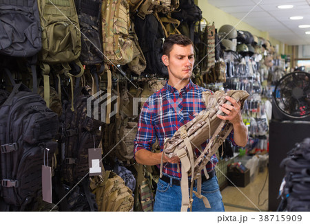 guy looking camouflage backpack in army store guy looking camouflage backpack in army store 38715909