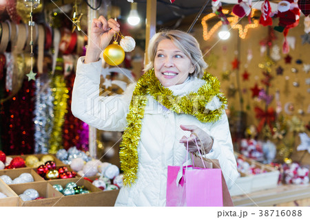 Smiling woman choosing Christmas toys at Christmas market Smiling woman choosing Christmas toys at Christmas market 38716088