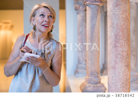 Mature female in art museum writing information Mature female in art museum writing information 38716542