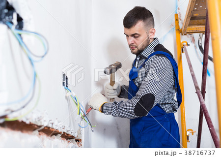 Craftsperson is beating the wall with a hammer Craftsperson is beating the wall with a hammer 38716737