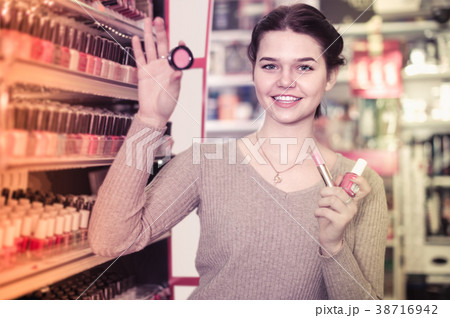Smiling woman customer deciding on make-up items in cosmetics shop 38716942