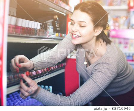 Smiling woman customer browsing rows of lipstick 38716946