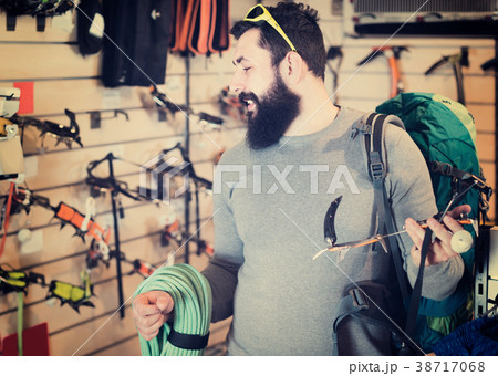 concentrated male customer examining climbing equipment in sports equipment store concentrated male customer examining climbing equipment in sports equipment store 38717068