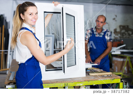 Portrait of female worker with finished plastic window in workshop Portrait of female worker with finished plastic window in workshop 38717382