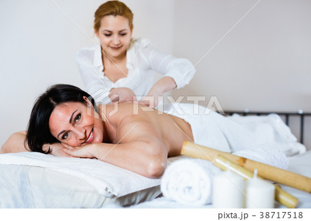 Young massagist doing shoulder massage to adult woman 38717518