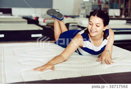 Female is lying on mattress for testing it in the store. 38717568