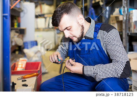 Worker repairs a plug with a screwdriver 38718125