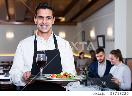 friendly waiter with serving tray welcoming to restaurant 38718226