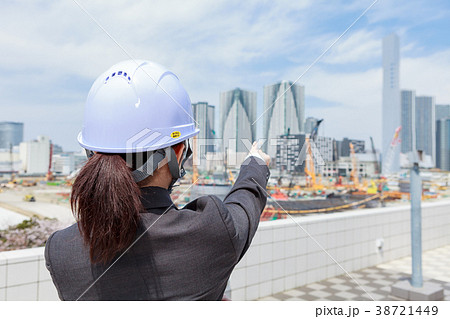 ヘルメットを着用したスーツの女性が 工事現場を望むの写真素材
