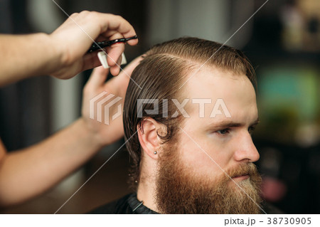 Barber using scissors and comb in barbershop 38730905
