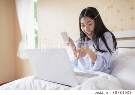 Excited woman with laptop sitting on bed. Excited woman with laptop sitting on bed. 38733938
