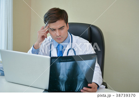 Smiling doctor posing in the office, he is wearing a stethoscope Smiling doctor posing in the office, he is wearing a stethoscope 38739370