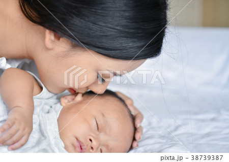 Newborn Concept. Mother and child on a white bed. Mom and baby b Newborn Concept. Mother and child on a white bed. Mom and baby b 38739387