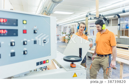 Carpenter in furniture factory inspecting piece in 38739820