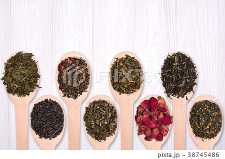 Set of different dry herbal teas in wooden spoons on a white wooden background Set of different dry herbal teas in wooden spoons on a white wooden background 38745486