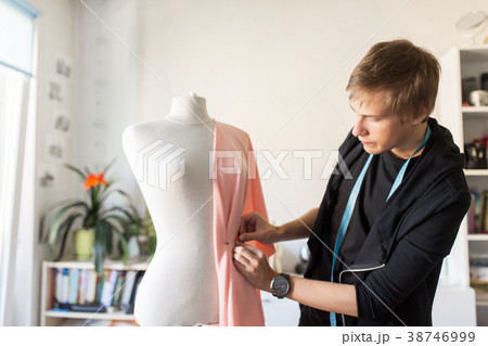 fashion designer with dummy making dress at studio 38746999