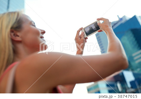 young woman with smartphone photographing city 38747015