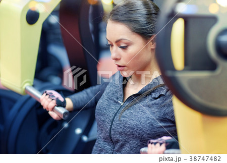 woman flexing muscles on chest press gym machine 38747482