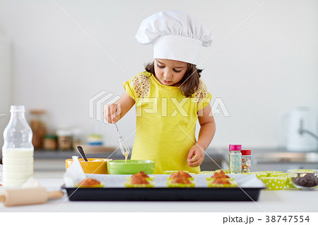 little girl in chefs toque baking muffins at home 38747554