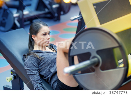 woman flexing muscles on leg press machine in gym woman flexing muscles on leg press machine in gym 38747773