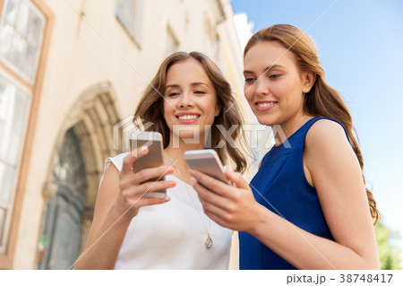happy women with smartphones on city street 38748417