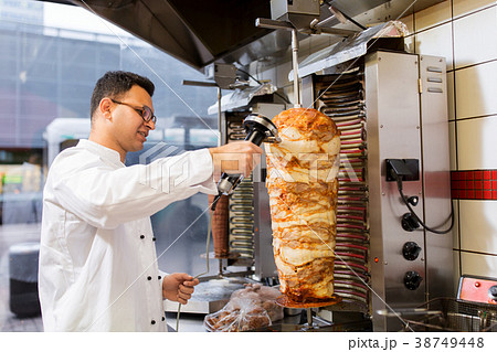 chef slicing doner meat from spit at kebab shop chef slicing doner meat from spit at kebab shop 38749448