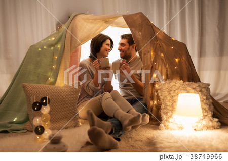 couple drinking coffee or tea in kids tent at home 38749966