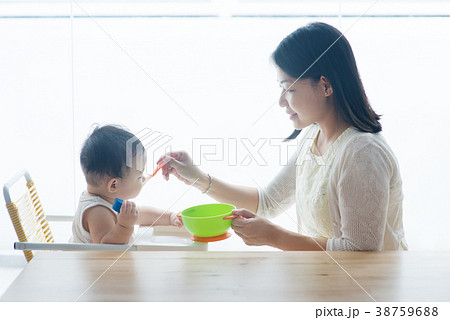 Mother feeding toddler. 38759688