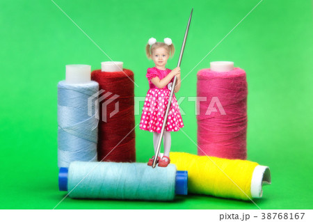 Little girl with a big needle for sewing on a green background. Little girl with a big needle for sewing on a green background. 38768167
