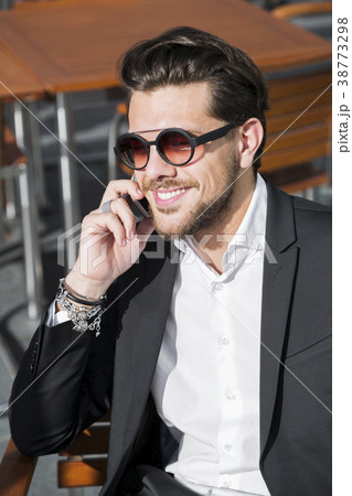 Man in black suit at table and talking on phone 38773298