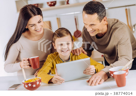 Cheerful parents watching a video together with Cheerful parents watching a video together with 38774014