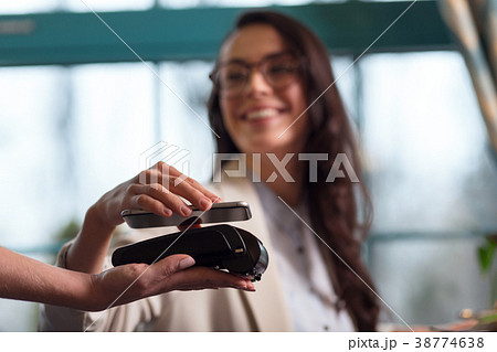 Cheerful merry woman paying with nfc technology 38774638