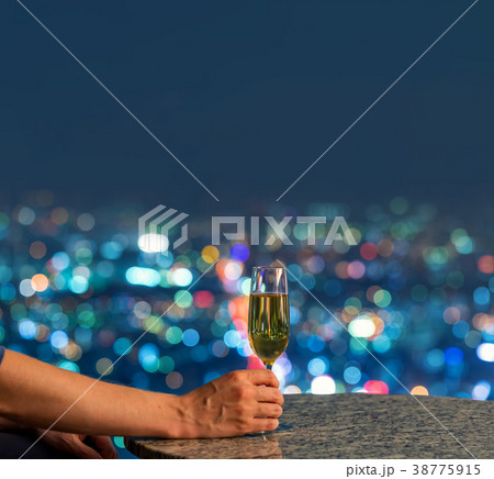 Man with wine high above the city at night 38775915