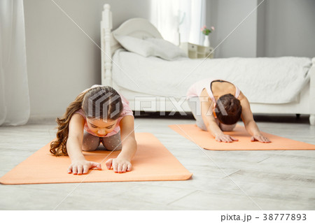 Concentrated girl doing exercises with her mom Concentrated girl doing exercises with her mom 38777893