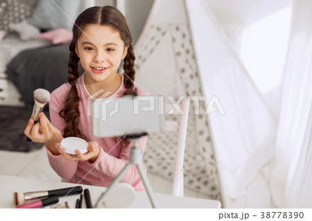 Cheerful girl doing makeup brush review 38778390