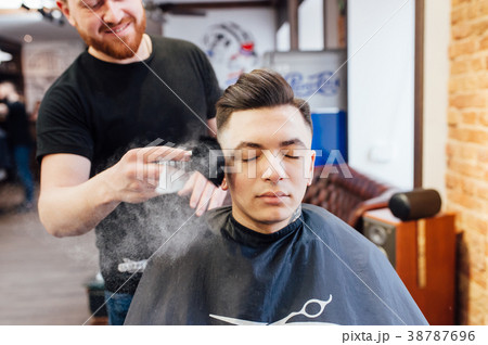 man is getting hairstyle at barber shop 38787696