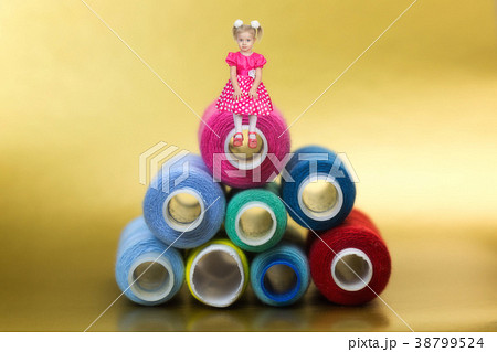 The girl sits at the top of a huge mountain of coils with sewing threads for 3 years. 38799524